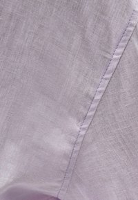 Light purple linen fabric featuring a fine texture with visible weaving patterns and a slightly shiny surface. Includes a sewn seam detail.
