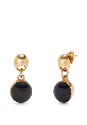 Boucles d'oreilles clous en or avec pendentifs en pierre ronde noire brillante, présentées sur un fond blanc.