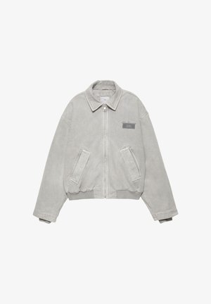 Siva denim jakna z zadrgo spredaj, z ostrim ovratnikom, dvema stranskima žepoma in manjšo logotipno značko na levi strani prsnega koša. Mehka, teksturirana površina.