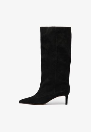 Juodas zomšu batus iki kelių su smailiu nosiu ir lieknu stiletto kulnu. Skirtas minimalus siūlių kiekis ir viso bato paviršius yra lygus.