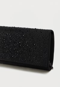 Čierna listová taška s textúrovaným povrchom, zdobená množstvom čiernych kryštálov, vytvárajúcich trblietavý vzor na exteriéri.