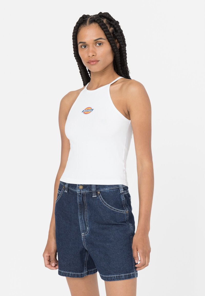 Hvit halterneck crop-top med en fargerik logo på brystet, sammen med mørkeblå høyt liv denimshorts med frontlommer og sømdetaljer.