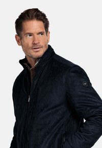 Donkerblauwe, met ritssluiting jack gemaakt van zachte, gestructureerde stof met een staande kraag en een logo-accent op de linkermouw.