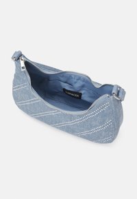 Petit sac à main en tissu bleu clair avec des rayures diagonales blanches à pois, fermeture éclair argentée ouverte et étiquette de poche intérieure visible indiquant "SVEN&ODD."
