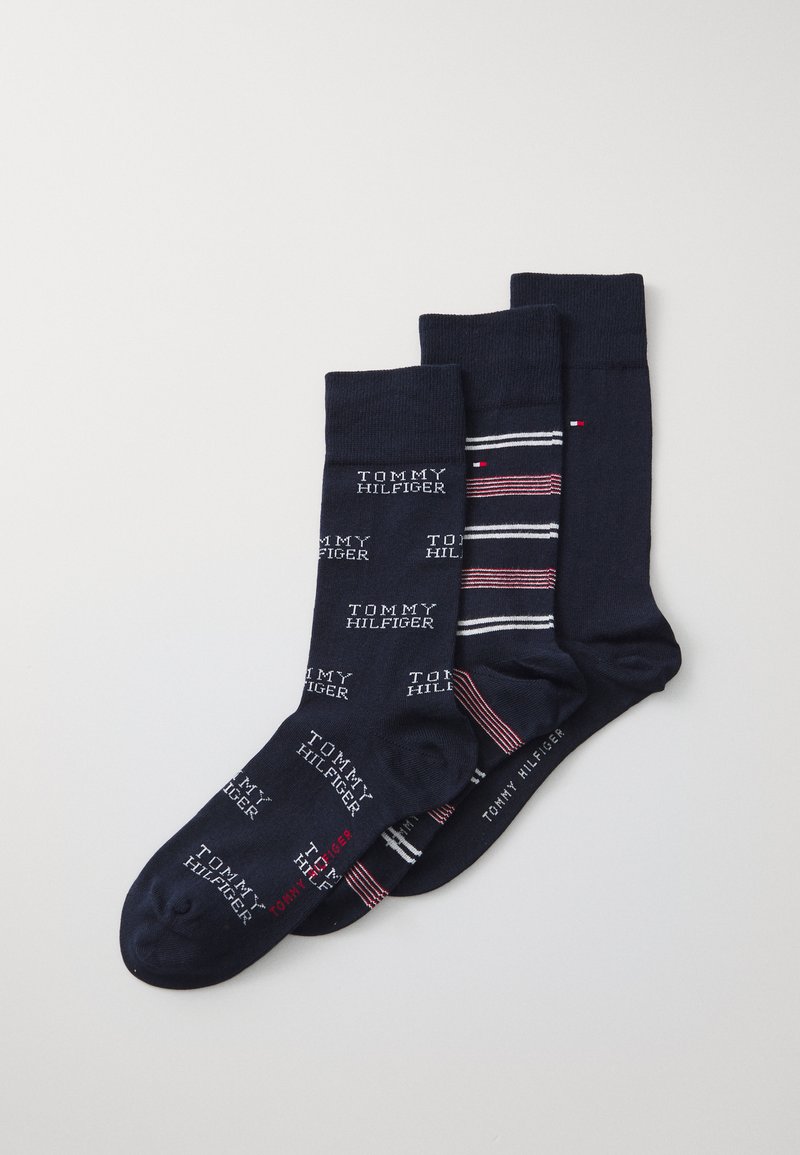 Tres pares de calcetines navy, uno con texto de logo repetido, otro a rayas con acentos rojos y blancos, y uno sólido navy con detalle de logo.