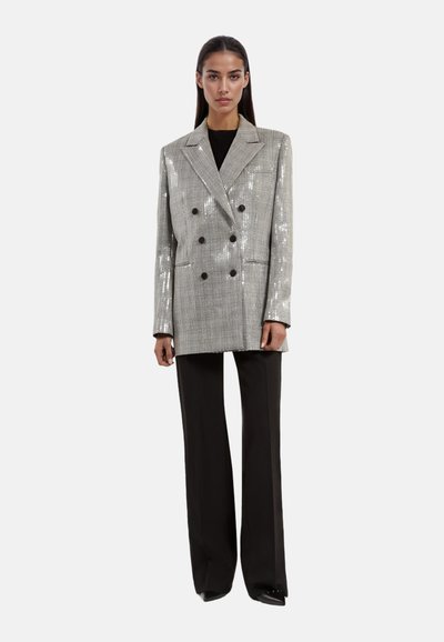 Zilveren pailletten dubbelknoop blazer met zwarte knopen, gesneden revers en twee voorkruiden, gecombineerd met zwarte wijde broek.