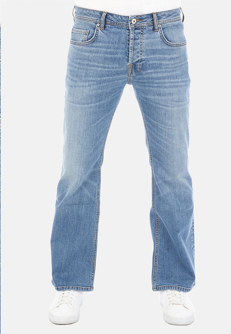 Jeans de mezclilla azul claro con corte recto, diseño estándar de cinco bolsillos y cierre de botón metálico. Llevados con zapatillas blancas.
