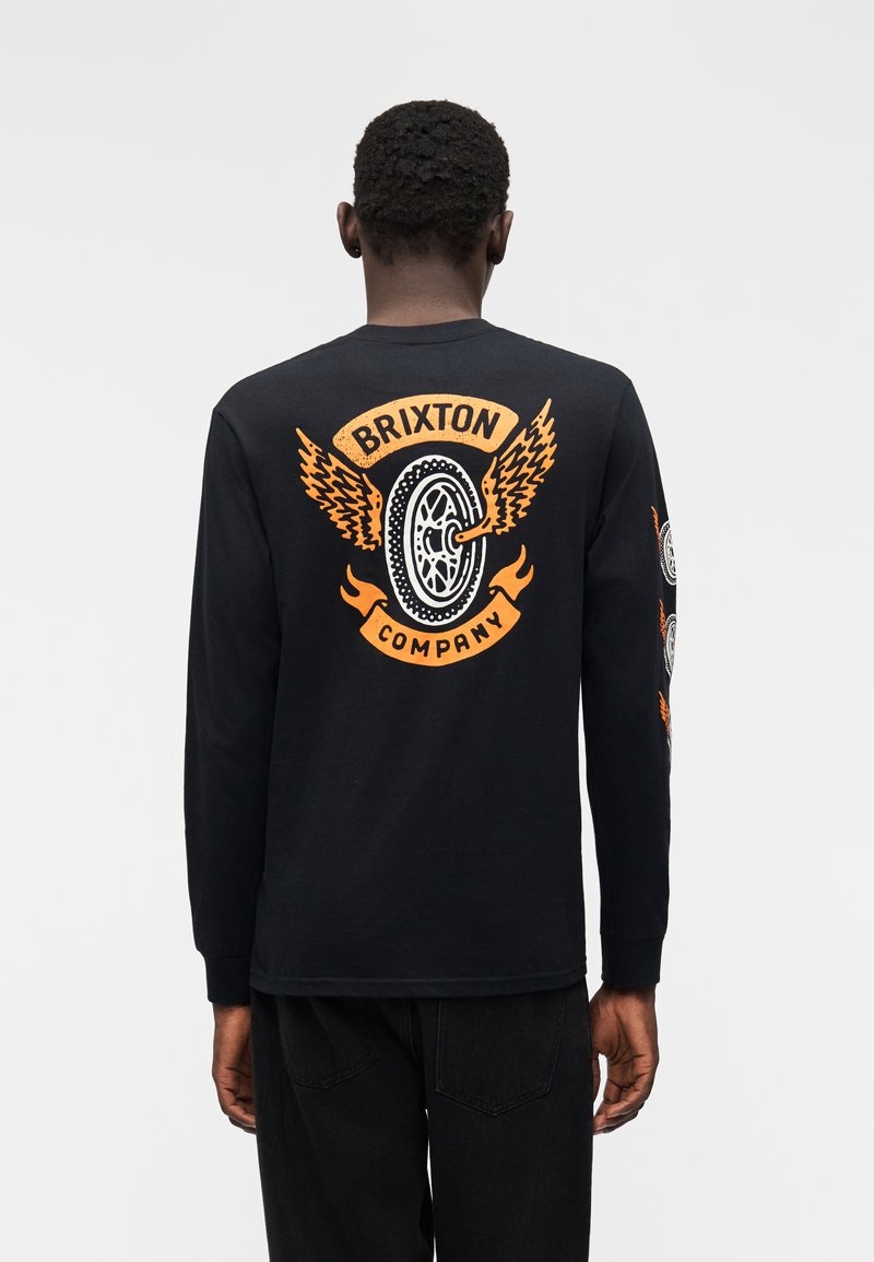Maglietta nera a maniche lunghe con grafica di una ruota alata arancione e testo "Brixton Company" sul retro. Parte anteriore liscia; materiale in cotone.