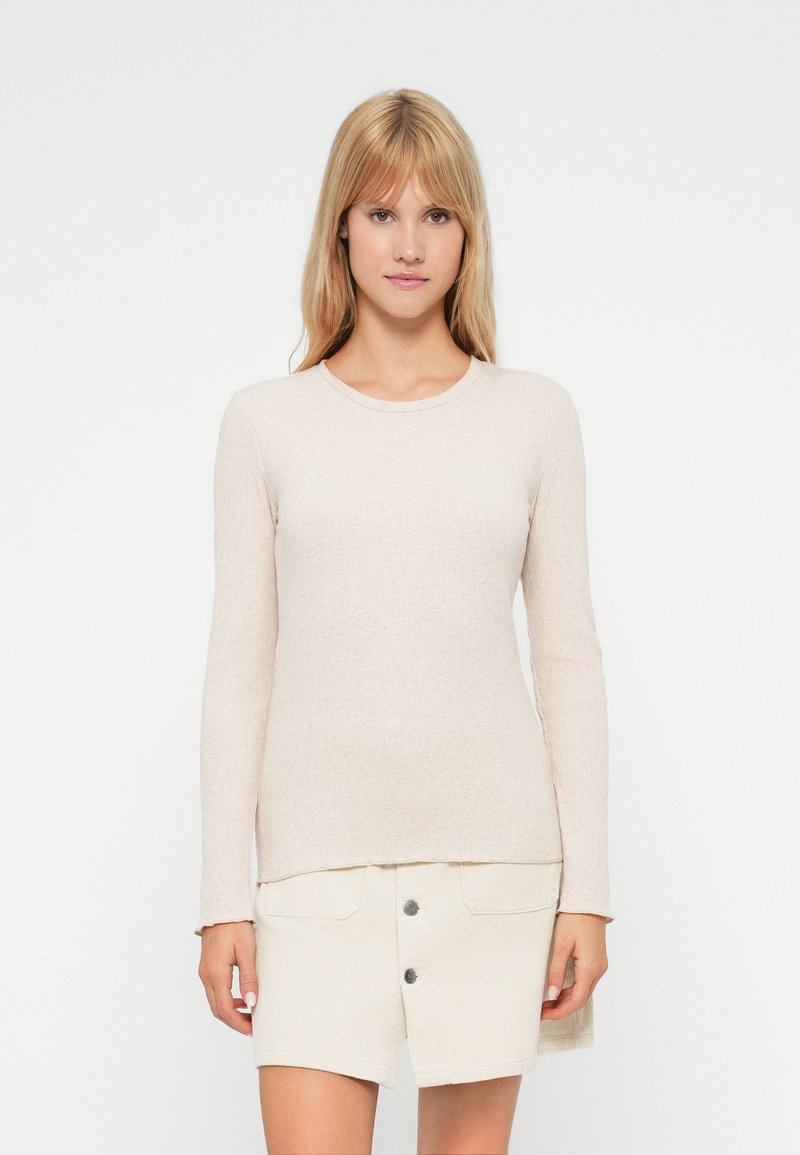 Beige langermet topp med ribbestruktur og rund hals, kombinert med et lyse farget skjørt med frontknapper og lommer.