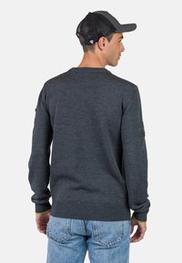 Grauer Strickpullover mit gerippten Bündchen und Saum, Rückansicht mit lässiger Passform. Kombiniert mit hellblauen Denim-Jeans.