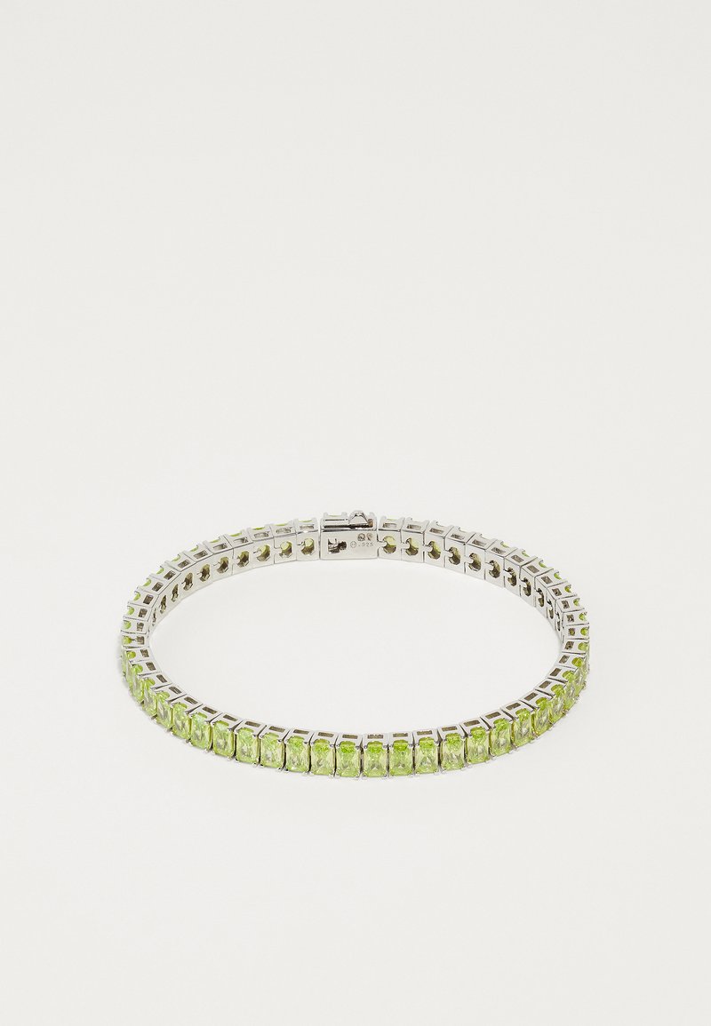 Bracelet en argent avec des pierres précieuses vertes, montées sur un bandeau fin et flexible au design géométrique. Texture lisse et fermoir sécurisé.