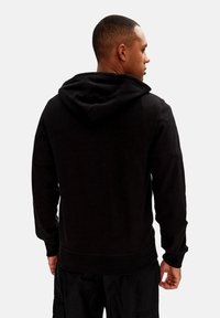 Felpa nera con cappuccio regolabile, maniche lunghe, polsini e orlo a costine. Tessuto morbido, design minimalista, dettagli di cucitura visibili.