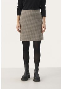 Rutig kjol i beige och svart, slim fit, knälång design, matchad med svarta strumpbyxor och kraftiga svarta kängor.