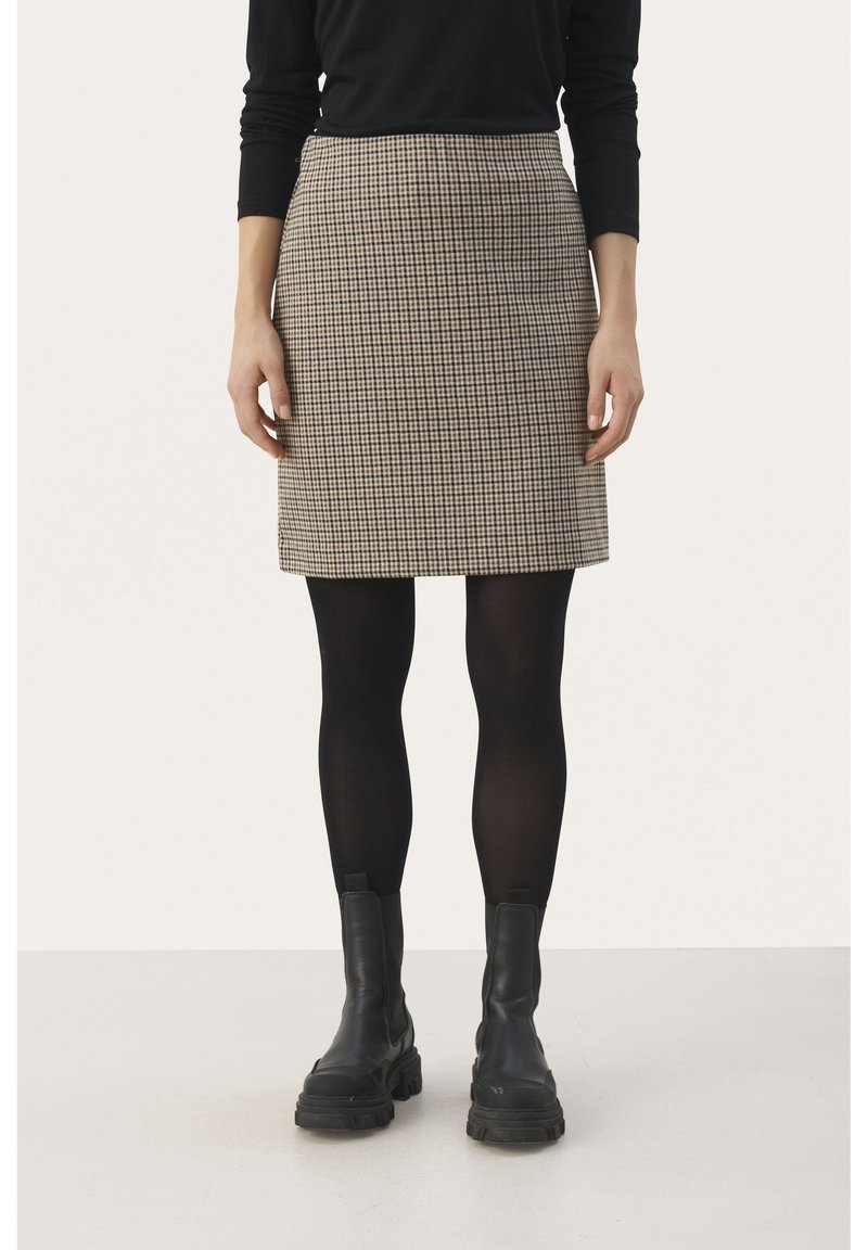 Rutig kjol i beige och svart, slim fit, knälång design, matchad med svarta strumpbyxor och kraftiga svarta kängor.