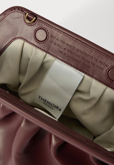 L'intérieur du sac en cuir bordeaux présente une doublure en tissu crème plissé. L'étiquette indique "THEMOIRÉ MADE IN ITALY". Comprend des accents en matériel doré.