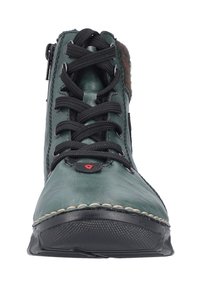 Zielony skórzany botek za kostkę z czarnymi sznurowadłami i zamkiem błyskawicznym, z teksturowaną gumową podeszwą i brązowym akcentem przy kołnierzu. Widoczne przeszycia.