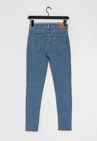 Kapehtavat farkut vaaleansinisestä denimistä, joissa on korkea vyötärö, kaksi takataskua ommelluilla yksityiskohdilla ja nahkalogo-patch.