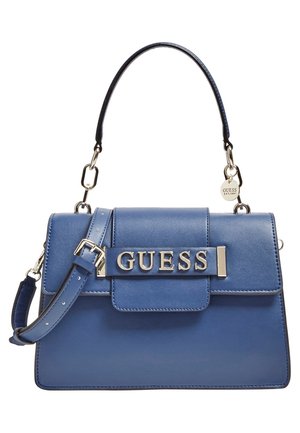 Blaue Lederhandtasche mit oberem Griff und verstellbarem Riemen, mit silberfarbener Hardware und "GUESS"-Logo auf der Vorderklappe.