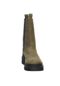 Bottine en daim vert olive avec panneaux élastiques noirs sur les côtés, semelle à crampons épaisse noire, et languettes à l'avant et à l'arrière.
