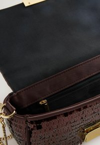 Braune, geprägte Handtasche mit goldfarbenem Verschluss. Innenfach mit Reißverschlusstasche und schwarzem Stofffutter. Strukturierte Oberfläche und schlankes Design.