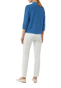Top blu ribbed con maniche a tre quarti, abbinato a pantaloni slim-fit bianchi e ballerine beige chiaro, visto da dietro.
