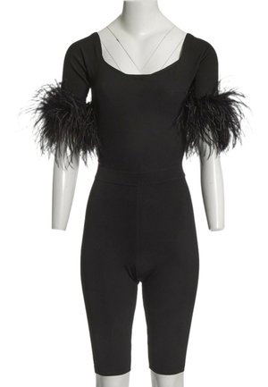 Combinaison noire moulante à manches courtes avec bordure en plumes noires aux bras, présentée sur un mannequin blanc.