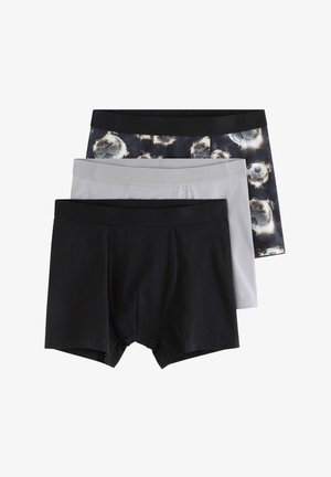 Tre par herreboxershorts stablet, med enkelt sort, enkelt grå og et sort par med et glødende mønster af en fodbold.