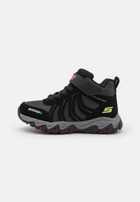 Scarpe da ginnastica nere impermeabili con una tomaia testurizzata, dettagli grigi e una chiusura a strap sicura. Presentano una suola resistente con trazione rossa.