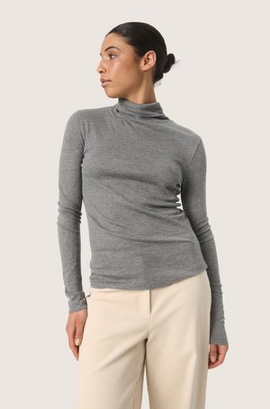 Maglione a maniche lunghe grigio a collo alto realizzato in materiale morbido, con un design aderente e polsini senza cuciture, abbinato a pantaloni beige.