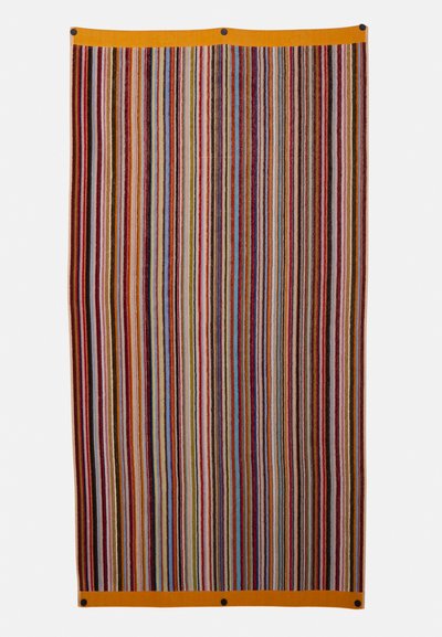 Tapis en tissu tissé présentant des rayures verticales de différentes couleurs, avec une bordure orange et des accessoires en noir en haut pour l'accrocher.