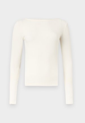 Top de manga larga color crema con ribetes, escote amplio tipo barco, silueta ajustada y líneas texturizadas verticales.