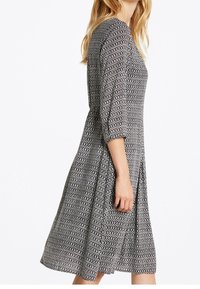 Vestido de estampado en blanco y negro con mangas tres cuartos, falda acampanada y escote redondo, hecho de una tela ligera.