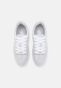Lys grå sneakers laget av semsket skinn og lær, polstret krage, hvite snørebånd og perforert tå for ventilasjon. Klassisk Vans-merkevare på innsiden.