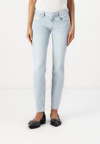 Ljusblå, raka jeans i denim med framfickor. Parat med svarta lägenheter med dekorativt hårdvara och remmar.