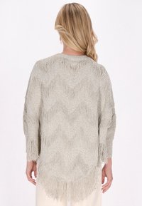 Cardigan grigio chiaro con frange, caratterizzato da un motivo zigzag texture, con maniche a tre quarti e orlo arrotondato.