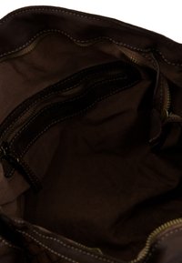 Wnętrze brązowej materiałowej torby z wieloma kieszeniami na zamek i kontrastującym przeszyciem. Miękka faktura, bez widocznych wzorów ani zdobień.