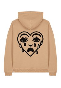 Felpa beige con un grande design di cuore ricamato nero, dotato di occhi e dettagli a lacrima, realizzata in tessuto morbido con polsini e orlo a costine.