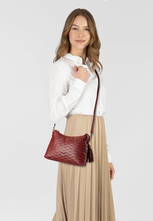 Rote Lederhandtasche mit einem gesteppten Muster, silberner Hardware und einer Quaste als Akzent. Kompakte Form, die mit einem Umhängegurt getragen wird.