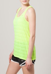 Neonowo żółta sportowa koszulka na ramiączkach z cienkimi paskami, teksturowanym wzorem i okrągłym dekoltem, w zestawie z czarnymi krótkimi spodniami sportowymi z białymi akcentami.