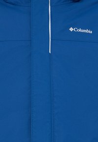 Zila jakna ar rāvējslēdzēju priekšpusē un baltu Columbia logotipu augšējā labajā stūrī, parādot auduma tekstūru un šuves detaļas.