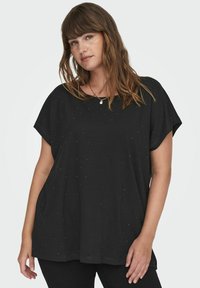 Zwarte T-shirt met korte mouwen en een oversized pasvorm, met een stippenpatroon van kleine, glanzende accenten door de stof. Zachte textuur.