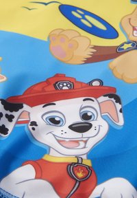 Tessuto a cartoni animati con un dalmata sorridente che indossa un casco da pompiere rosso, sfondo blu brillante e colori vivaci con dettagli giocosi.