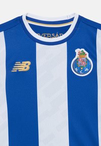 Fotbollströja med blå och vita vertikala ränder. Tillverkad av texturerat tyg, med en guld "NB"-logotyp och en cirkulär klubbemblem.