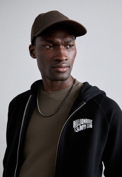 Sort zip-up hoodie med "Billionaire Boys Club" logo, olivengrøn skjorte under, og en brun baseballkasket. Har en sølv kædehalskæde.