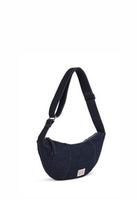 Borsa a spalla in denim blu scuro con forma curvata, chiusura con zip e tracolla regolabile caratterizzata da cuciture a contrasto e un patch con logo.