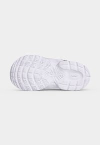 Σόλα λευκού αθλητικού παπουτσιού Nike με υφασμένους λαβή μοτίβων και το λογότυπο Nike ορατό κοντά στη φτέρνα.