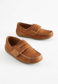 Mocassins en cuir marron avec un design de type mocassin, dotées d'une sangle et d'une couture décorative le long des bords et de l'orteil. Semelle extérieure en caoutchouc plate.