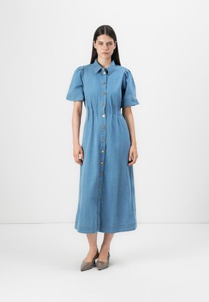 Denim srajčna obleka v svetlo modri barvi, s kratkimi nabranimi rokavi, gumbi spredaj in zoženim pasom. Okrašena z zlatimi gumbi, do gležnjev.