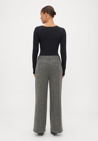 Melna garām piedurknēm bodijs, apvienots ar pelēkajām zīda platām biksēm. Gluda auduma, pieguļošs siluets un augstā jostas dizains.