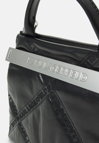 Zwarte leren handtas met een geometrisch ontwerp, zilveren hardware met het "KARL LAGERFELD" logo en gestructureerde handvatten.